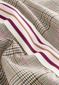 Tissu tricoté multicolore présentant un motif pied-de-poule et des rayures dans des tons de marron, crème, rose et violet foncé avec une surface texturée.