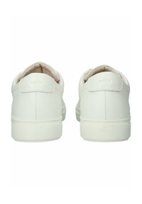 Baskets en cuir blanc avec une texture lisse, un dos arrondi, un col rembourré et une semelle en caoutchouc, avec un marquage minimal sur le talon.