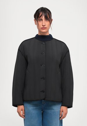 Schwarze gepolsterte Jacke mit rundem Kragen, sechs Knöpfen und zwei seitlichen Taschen. Verfügt über eine vertikale Stepptextur und einen gerippten marineblauen Kragen.