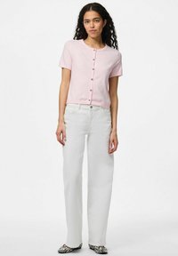 Kortärmad rosa stickad kofta med silverknappar, tillsammans med högmidjade vita jeans och svartvitrandiga slitna skor.