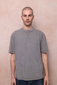Grijze oversized t-shirt met een ronde halslijn, korte mouwen en groene stiksels. Bevat subtiel het woord "Rugged" in het ontwerp.