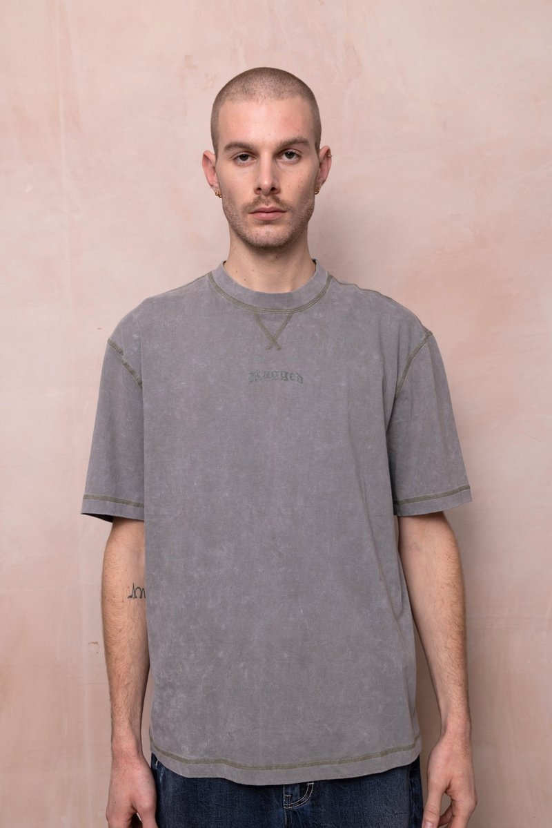 Grijze oversized t-shirt met een ronde halslijn, korte mouwen en groene stiksels. Bevat subtiel het woord "Rugged" in het ontwerp.