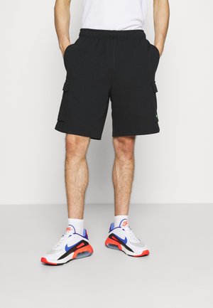 Shorts cargo noirs avec une taille élastique, comprenant deux poches latérales et une poche cargo, assortis à des baskets Nike blanches et rouges.