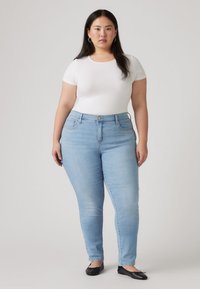 Φωτεινά γαλάζια στενά τζιν από τζιν ύφασμα, με κλασικό σχέδιο πέντε τσεπών και μέση μεσαίου ύψους. Συνδυάζονται με λευκό κοντομάνικο τοπ.