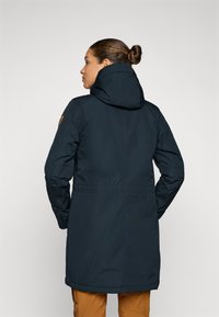 Blauw lange jas met capuchon, voorzien van een koord in de taille, elastische manchetten en een logo-opdruk op de mouw. Glad, weersbestendig materiaal.