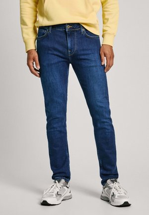 Jeans de mezclilla azul slim-fit con un diseño clásico de cinco bolsillos, detalles de costura y cierre de cremallera con botón.