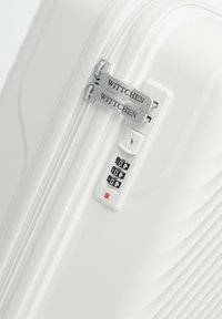 Maleta rígida blanca con ondas en relieve, cremalleras dobles etiquetadas "WITTCHEN," candado de combinación numérico con indicador rojo, diseño elegante.