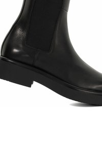 Zwarte leren enkellaars met elastische zijpanelen, ronde neus en platte rubberen zool, met een gladde textuur en minimale details.