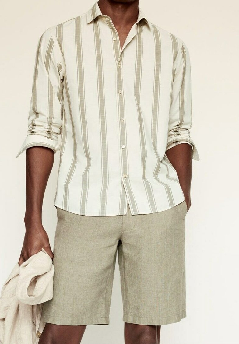 Licht gestreept overhemd met knopen in beige en olijfgroene tinten, gecombineerd met olijfgroene shorts. De stof lijkt licht en getextureerd.