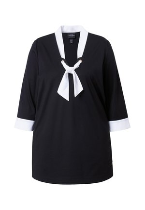 Czarna bluzka z białym kołnierzykiem i mankietami, z białą kokardą przy dekolcie i rękawami o długości do połowy przedramienia.