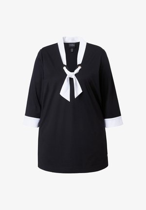 Czarna bluzka z białym kołnierzykiem i mankietami, z białą kokardą przy dekolcie i rękawami o długości do połowy przedramienia.