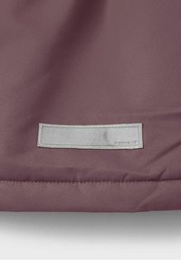 Fialová látka s texturovaným povrchem, na spodním okraji je přišitá stříbrná obdélníková visačka s embosovaným nápisem "nomert".