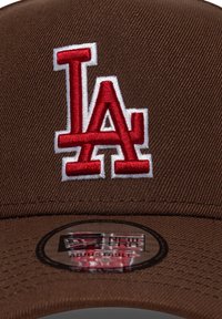 Καφέ μπέιζμπολ καπέλο με ανάγλυφο κόκκινο και λευκό λογότυπο "LA", υφασμένο με υφή και κυκλικό ρυθμιζόμενο ταμπελάκι στο γείσο.
