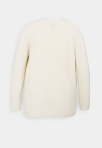 Maglione a maglia beige chiaro con finitura testurizzata, maniche lunghe e scollo rotondo. Presenta maniche a raglan e una vestibilità ampia e comoda.