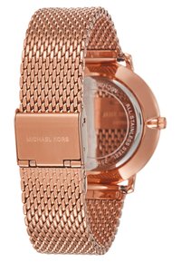 Montre en métal rose doré avec un bracelet en maille tissée, cadran circulaire et fermoir gravé du nom de la marque. Fond en verre avec acier inoxydable.