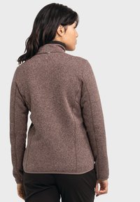 Dunkelbraune Fleecejacke mit hohem Kragen, strukturiertem Stoff und kontrastierenden Nähten. Figurbetonter Schnitt mit leicht tailliertem Saum.