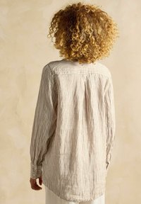 Dlhý rukáv pruhovaná košeľa s víťaznou béžovou a svetlo hnedou farebnou schémou, vyrobená z mäkkej látky s uvoľneným strihom a gombíkovými manžetami.