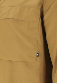 Korte mouwen, mosterdgele shirt van gladde stof met een borstzak en een klein logotag aan de zoom.