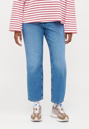 Light blue straight-leg jeans with a faded wash, paired with a red and white striped long-sleeve shirt and gray-brown sneakers.