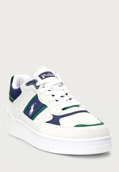 Valkoinen nubukinen lenkkari, jossa on laivastonsinisiä ja vihreitä yksityiskohtia. Kenkässä on pyöreä kärki, nauhakiinnitys, logotunnistus sivussa ja paksu valkoinen pohja.