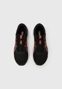 Svarte atletiske sko med meshoverdel, røde detaljer og grå gummisåler. Har snøring og merket tungelapp.