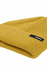 Berretto a maglia giallo senape con texture a coste e un'etichetta nera che recita "CHASIN'" di lato. Design piegato.