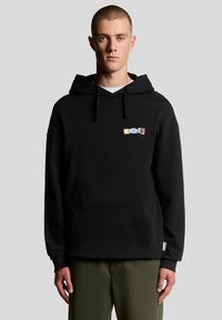 Juodas džemperis su gaubtu, priekyje kišenė, su raišteliais gaubto reguliavimui ir spalvingu grafinio teksto užrašymu ant krūtinės. Audinys atrodo minkštas, su laisvu siluetu.