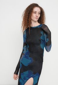 Φόρεμα με μακριά μανίκια, με σκουρόχρωμο φόντο και μπλε και τιρκουάζ αφηρημένα σχέδια, εφαρμοστή σιλουέτα και σκίσιμο μέχρι το μηρό στη μία πλευρά.