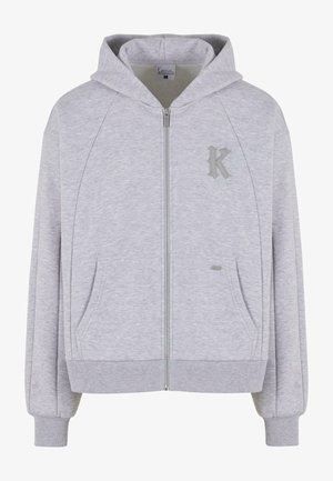 Hellgraue Zip-Hoodie mit weicher Textur, ausgestattet mit einer Kapuze, Fronttaschen und einem dezenten, geprägten "K"-Logo auf der linken Brust.