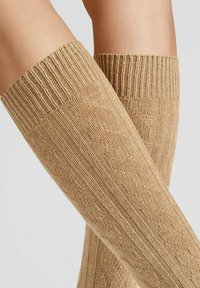 Knee-high, light brown knitted socks featuring a ribbed top and diamond pattern texture. Material appears soft and stretchy.