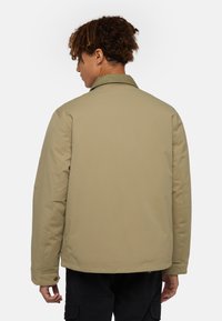 Beige padded jacket with a corduroy collar, featuring a back yoke seam and a left arm pocket, designed with a relaxed fit.