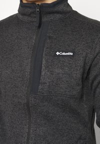 Veste en polaire Columbia gris foncé à fermeture éclair, avec col montant et panneau zippé noir sur la poitrine supérieure.