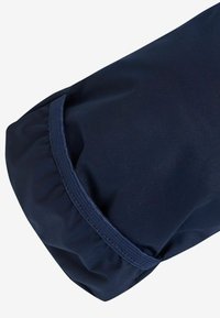 Donkerblauwe stof met een gladde textuur, met een geplooid manchet en contrasterende stiksels. Rondvorm met een flexibele vormgeving.