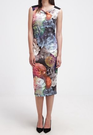 Sleeveless, knee-length dress with large colorful floral print worn with black pointed-toe heels on a white background.