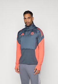 Mørkegrå og lys koral sports-pullover med halv lynlås, med et logo og stribede detaljer, lavet af glat, letvægtsstof.