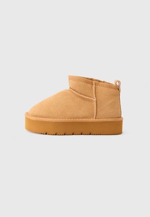 Stivaletti alla caviglia color sabbia in suede, con punta arrotondata, cuciture sottili, una texture morbida e una suola in gomma spessa e testurizzata.
