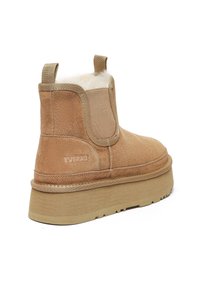 Tansuede Stiefelette mit elastischen Seitenteilen, weichem Innenfutter und einer dicken, tanfarbenen Gummisohle. Dezente Markenkennzeichnung an der Außenseite.