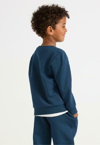 Felpa di colore blu navy con scollatura rotonda a costine e polsini, realizzata in un tessuto testurizzato. Presenta una vestibilità comoda e tasche laterali.