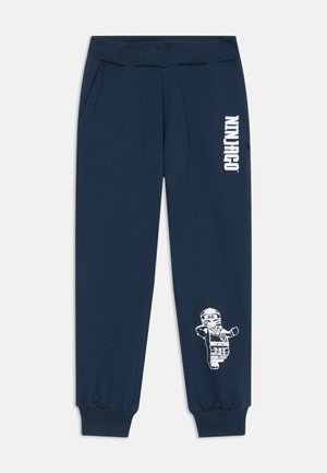 Marineblaue Sweatpants mit geripptem Bund, seitlichen Taschen, schmal zulaufenden Bündchen und einem weißen "Ninjago"-Logo mit einem Lego-Charaktergrafik.