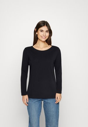 Zwarte top met lange mouwen en een ronde halslijn, gemaakt van zachte stof. Gepaard met lichtblauwe jeans met een relaxed fit.