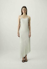 Hosszú, fehér ruha, sima, testhez simuló felsőrésszel és francia részletekkel az alján, vékony pántokkal és aszimmetrikus dizájnnal.