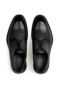 Chaussures habillées en cuir noir avec une finition lisse, bout rond et lacets fins. Le design minimaliste et les semelles légèrement rembourrées sont visibles.
