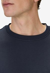 Mörkblå sweatshirt med rund halsringning och ribbat krage. Tyget verkar slätt med en medelviktig textur och minimalt med detaljer.