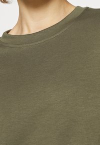 Olive green crewneck sweatshirt made from soft fabric. Features a smooth texture and minimal stitching details around the neckline.