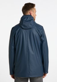 Giacca impermeabile blu navy con cappuccio, tessuto liscio, polsini elasticizzati e taglio dritto. Caratterizzata da una ventola posteriore per una migliore circolazione dell'aria e comfort.