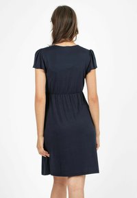 Granatowa sukienka z krótkimi bufkami, elastycznym pasem i długością do kolan. Wykonana z miękkiego, lekkiego materiału o gładkiej teksturze.