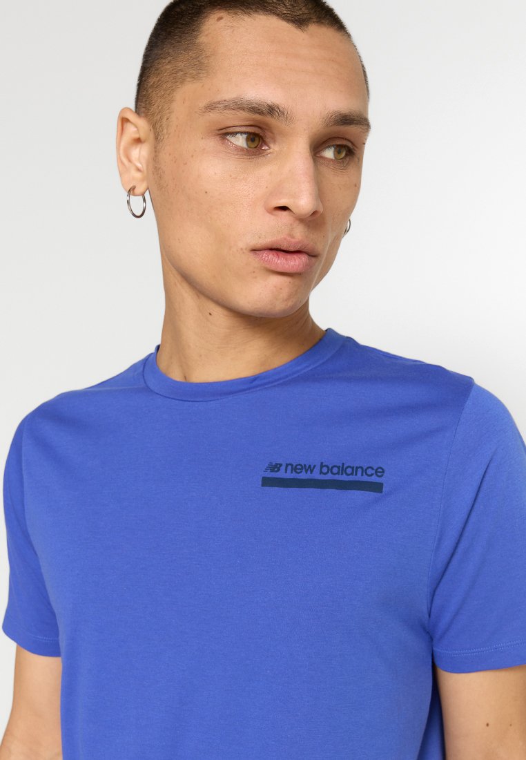 Camiseta de manga corta azul real hecha de algodón suave. Presenta el logo en marinero de "New Balance" y un cuello redondo con una textura suave.