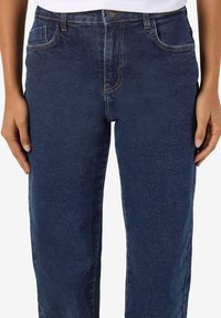 Tamsiai mėlynos džinsinės kelnės su klasikinio dizaino. Ypatybės: penki kišenės, diržo kilpos ir matomos siuvimo detalės. Tiesus kojų kirpimas.