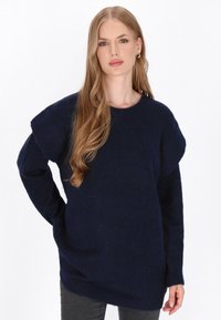 Granatowy sweter dzianinowy z długimi rękawami, opadającymi szwami na ramionach i ściągaczami przy mankietach. Miękka tekstura, luźny krój oraz okrągły dekolt.
