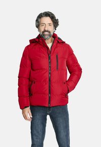 Chaqueta acolchada roja con capucha, que cuenta con un cierre frontal y dos bolsillos laterales. Detalles de cremallera negra y textura acolchada en toda la prenda.